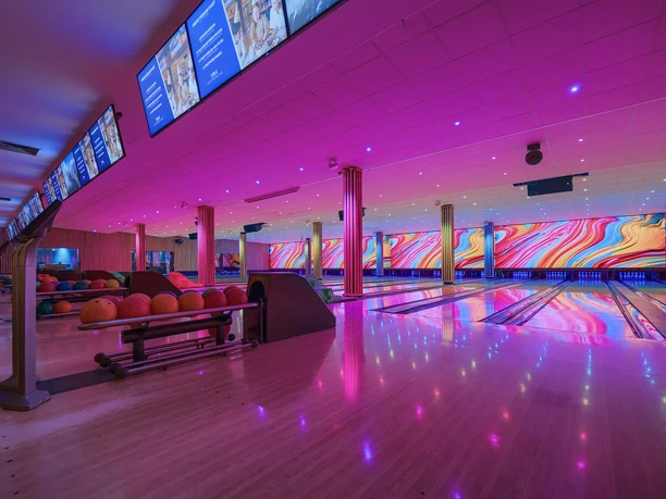 Bowling Bahnen bei West Bowling Eine moderne Bowlinghalle mit farbenfroher LED-Beleuchtung, leuchtende Bahnen und bunte Kugeln.