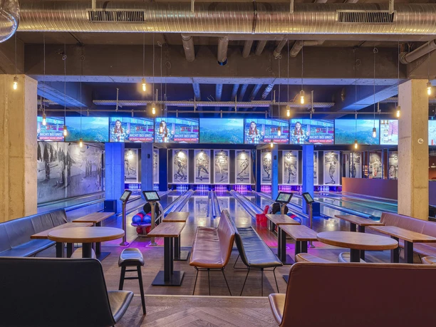 Bowling lanes at Underlux Interior of the Underlux bowling center with blue and purple lights, tables in the foreground.