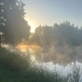 Quellsee am Morgen.jpg Morgennebel umhüllt einen ruhigen See, während Sonnenlicht durch den dichten Wald schimmert.