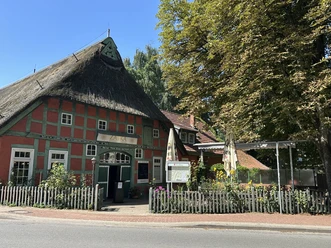 Zaika Restaurant und Tapas Bar von außen Fachwerkhaus mit Reetdach und grünen Balken, davor Terrasse mit Sonnenschirmen und Blumen.