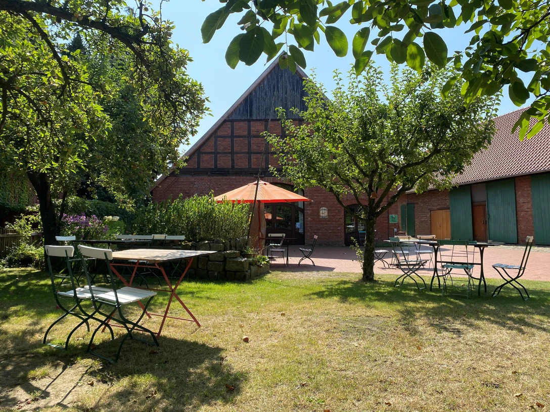 Biobäckerei Honeck Biobäckerei Honeck mit Fachwerk-Ambiente und Gartenmöbeln unter einem Sonnenschirm im Grünen.