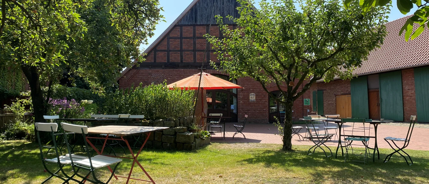 Biobäckerei Honeck Biobäckerei Honeck mit Fachwerk-Ambiente und Gartenmöbeln unter einem Sonnenschirm im Grünen.