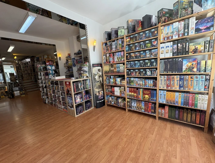 Eingangsbereich Brave New World Ein lichtdurchfluteter Raum voller Gesellschaftsspiele, die in hohen Regalen perfekt zur Schau gestellt sind.A light-flooded room full of board games, perfectly displayed on high shelves.