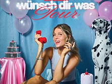 Eine junge Frau sitzt mit einem roten Telefon in der Hand. Daneben steht ein Dalmatiner vor bunten Ballons.