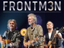 Drei Musiker mit Gitarren performen Seite an Seite auf einer Bühne, Atmosphäre wirkt lebendig.