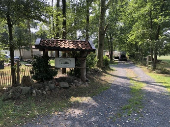 Naturcampingplatz "Im Braucke" Eingang des Naturcampingplatzes "Im Braucke" mit Holzschild, umgeben von hohen Bäumen und Kiesweg.Entrance to the natural campsite "Im Braucke" with wooden sign, surrounded by tall trees and gravel path.Indgang til den naturlige campingplads "Im Braucke" med træskilt, omgivet af høje træer og grussti.Ingang van de natuurcamping "Im Braucke" met houten bord, omgeven door hoge bomen en grindpad.