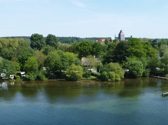 Campingplatz Zur schönen Aussicht_Luftaufnahme Grüne Bäume umgeben einen See. Boote liegen am Steg.