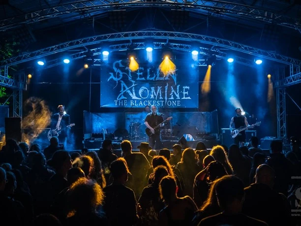 Stella Nomine Festival Torgau4, Fotoquelle_ SchwarzePresse.de, Fotograf Gerald Krauser .jpg Open-Air-Konzert bei Nacht mit Band auf beleuchteter Bühne, Publikum im Vordergrund.