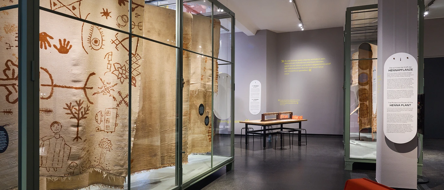 Exhibition of antique textiles in glass showcases in a modern museum hall.