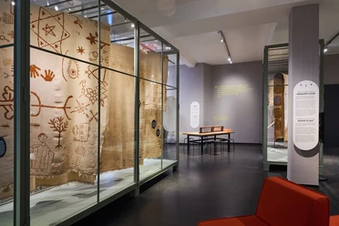 Ausstellung SCHUTZ Foto Tom Dachs.jpg Ausstellung mit antiken Textilien in Glasvitrinen in einem modernen Museumssaal.