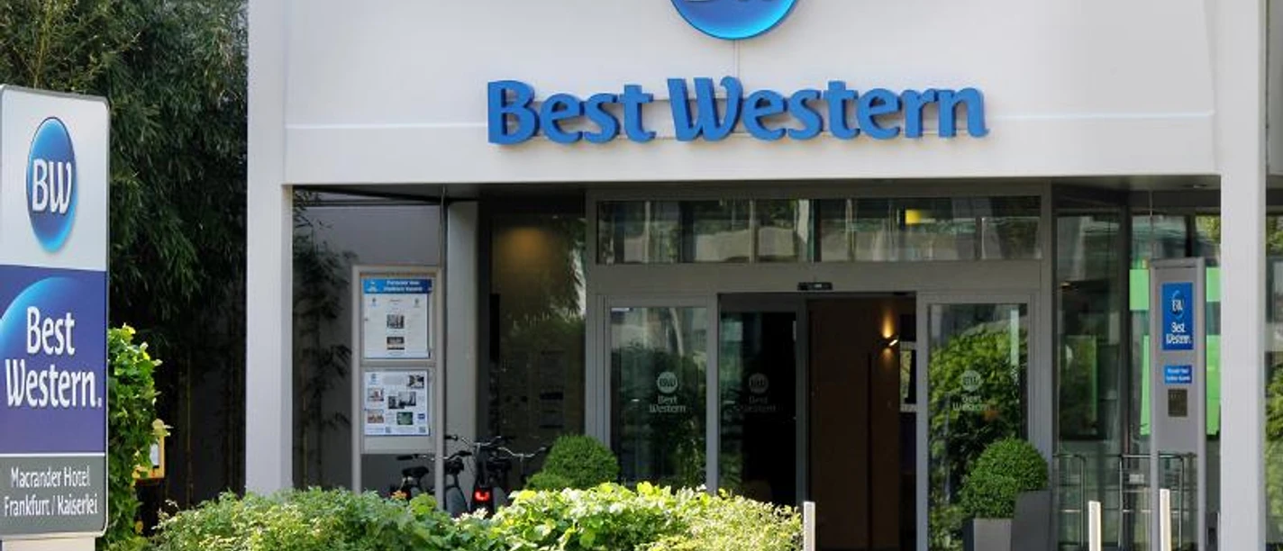 Best Western Macrander Hotel FrankfurtKaiserlei Ein Best Western Hotel Eingang mit blauem Logo und grünen Büschen.