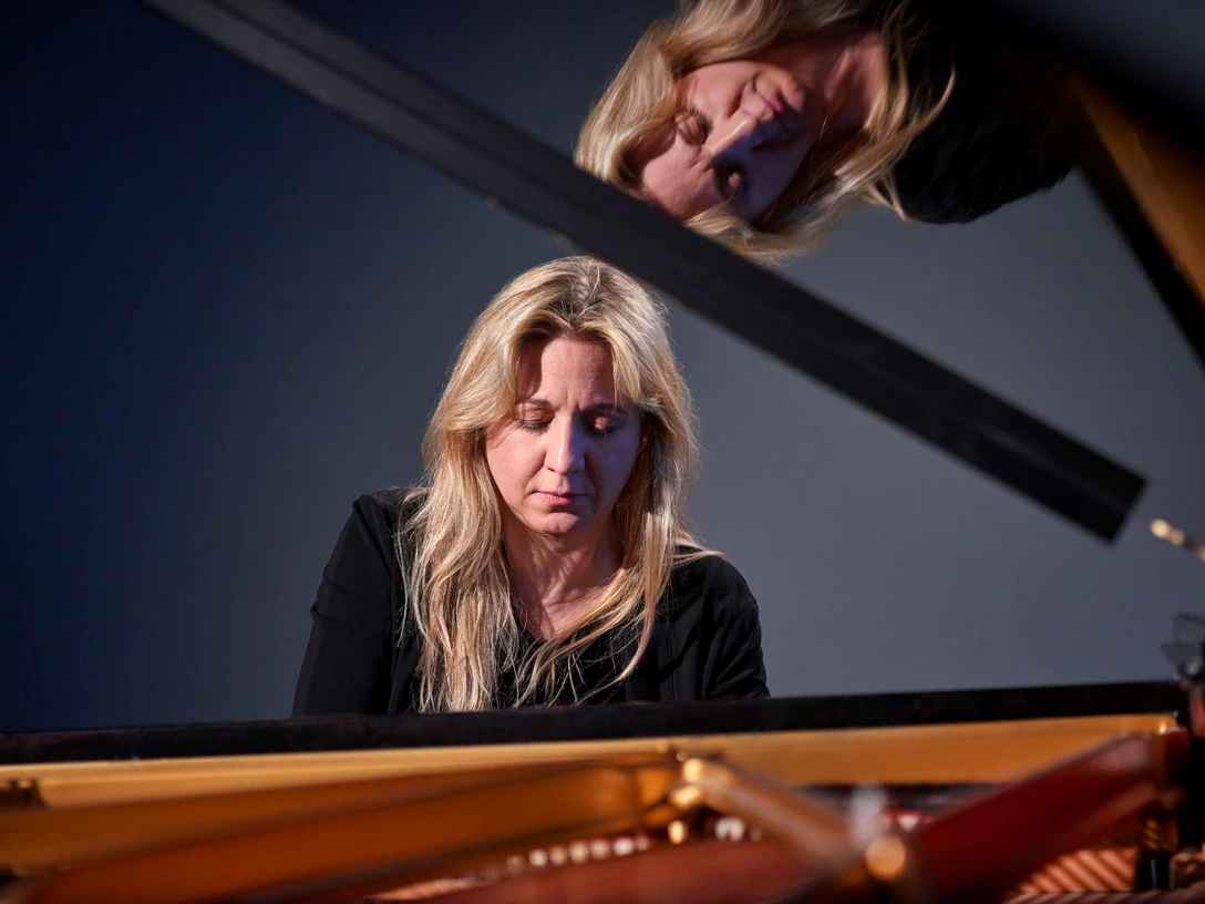 Ragna Schirmer Die Pianistin Ragna Schirmer vertieft am Flügel, mit einem reflektierenden Spiegelbild darüber.