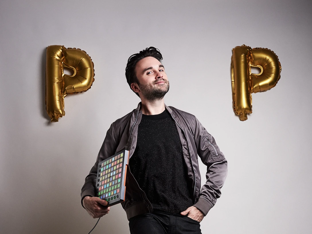 Dr.Pop Ein Mann, der Musik aus einem Gerät steuert, springt leichtfüßig vor hellem Hintergrund.