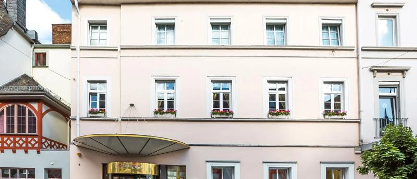Dom Hotel Limburg Ein rosafarbenes Hotelgebäude "Dom Hotel Limburg" mit Blumenkästen an den Fenstern.