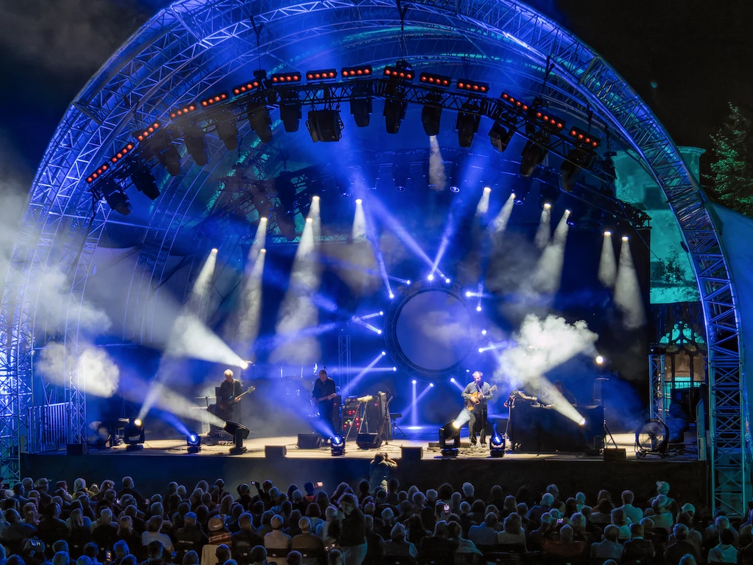 Kings of Floyd - „Dark Side“-Tour 2026 Open-Air-Konzert bei Nacht mit blauer Bühnenbeleuchtung und einem großen, gefüllten Zuschauerbereich.