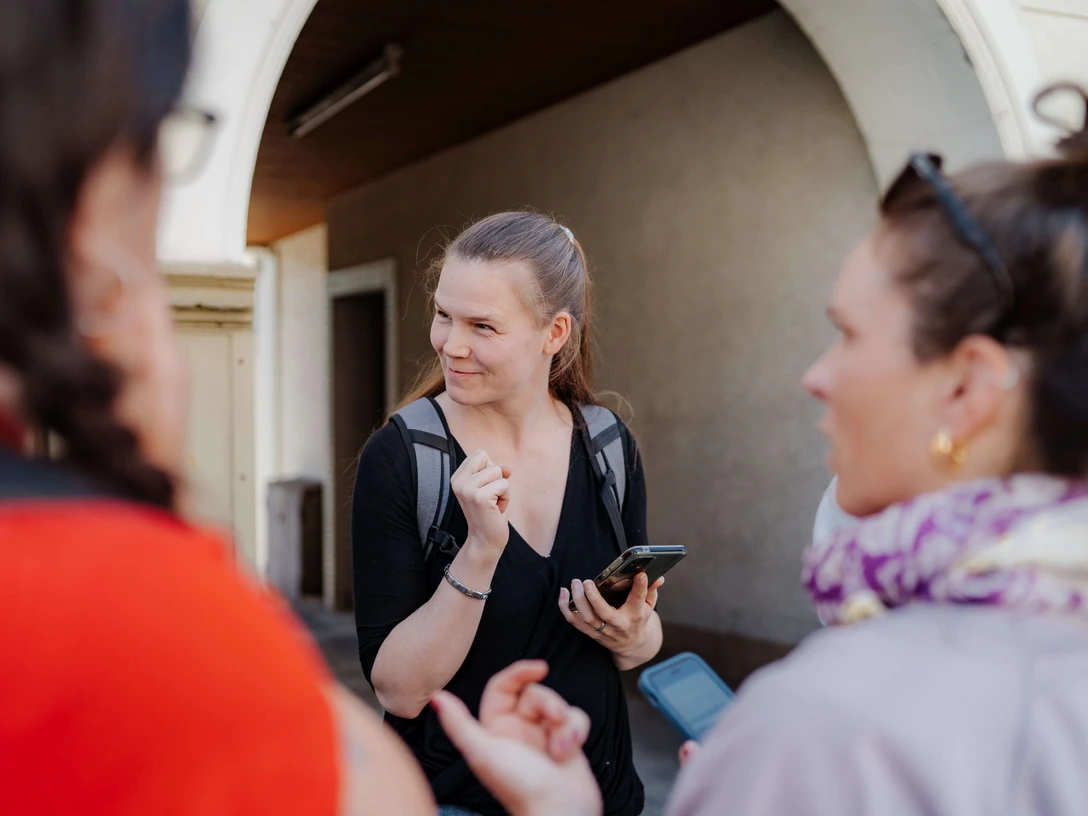 Rätseltour Heiligenhaus Junge Erwachsene stehen im Gespräch mit Smartphones in der Hand, vor einem Torbogen in Heiligenhaus.