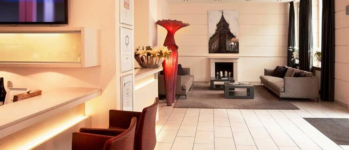 Hotel Hamburger Hof Eine moderne Hotellobby mit Bar, Sitzgelegenheiten und einem Kamin.