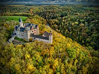Lunzenau_Schloss Rochsburg_(c)Instagram _lng_photography__CC BY-SA (1).JPEG La foto mostra una veduta aerea del castello di Rochsburg. Il castello è circondato da una scintillante foresta autunnale dorata.