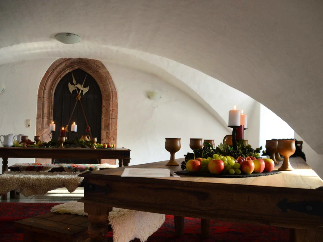 Jagen-Tafeln-Schmausen Schloss Rochsburg Auf einem Holztisch im Schloss stehen ein Obstteller und Weinkelche.A plate of fruit and goblets of wine are placed on a wooden table in the castle.Na dřevěném stole v zámku je položen talíř s ovocem a poháry s vínem.Na drewnianym stole w zamku umieszczono talerz z owocami i kielichy z winem.Een bord fruit en bekers wijn staan op een houten tafel in het kasteel.Un piatto di frutta e calici di vino sono disposti su un tavolo di legno nel castello.