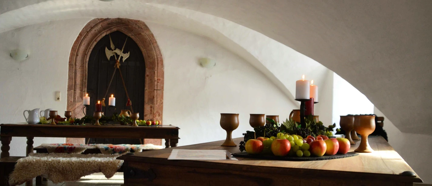 Jagen-Tafeln-Schmausen Schloss Rochsburg Auf einem Holztisch im Schloss stehen ein Obstteller und Weinkelche.