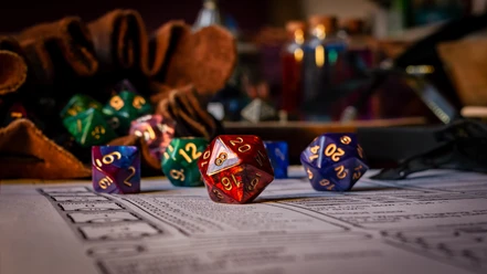 AdobeStock_504791075_Copyright stock.adobecom Est Bunte Rollenspielwürfel auf Charakterbogen, mit Lederbeutel und Fläschchen im Hintergrund