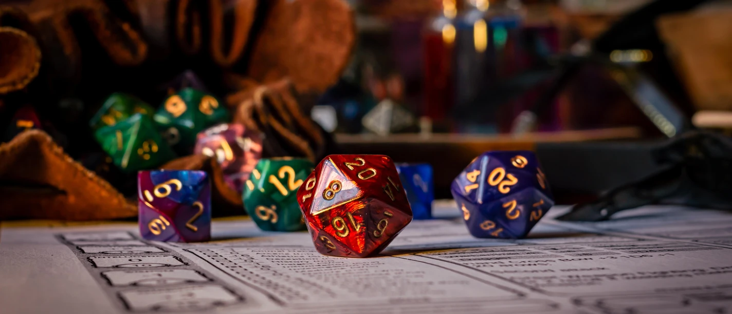 Bunte Rollenspielwürfel auf Charakterbogen, mit Lederbeutel und Fläschchen im Hintergrund