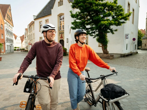 Warendorf Twee fietsers met helmen op een historische, geplaveide straat in het stadscentrum.