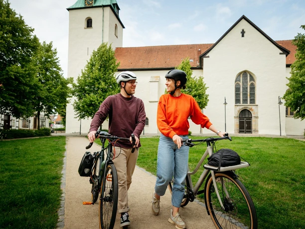 Dissen Twee fietsers met helmen lopen over een pad voor een historische kerk.