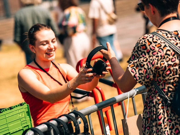Even Flow Festival 2025 A person hands a headset to a guest over a table full of audio equipment.