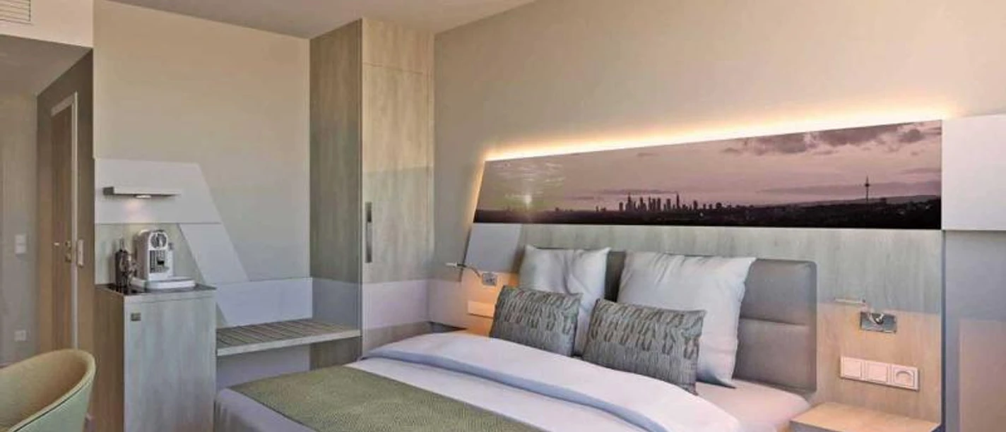 Holiday Inn Frankfurt Airport Ein modernes Hotelzimmer mit großem Bett, Minibar und Stadtbild an der Wand.