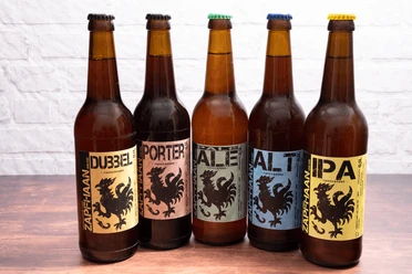 Alle fünf Biersorten von Zapfhaan aus Haan Fünf Zapfhaan Biersortenflaschen in Haan vor weißem Hintergrund, jede mit einem markanten Etikett.