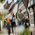 Unterwegs in der Altstadt von Osnabrück Zwei Personen laufen mit Fahrrädern durch eine gepflasterte Straße mit Fachwerkhäusern.