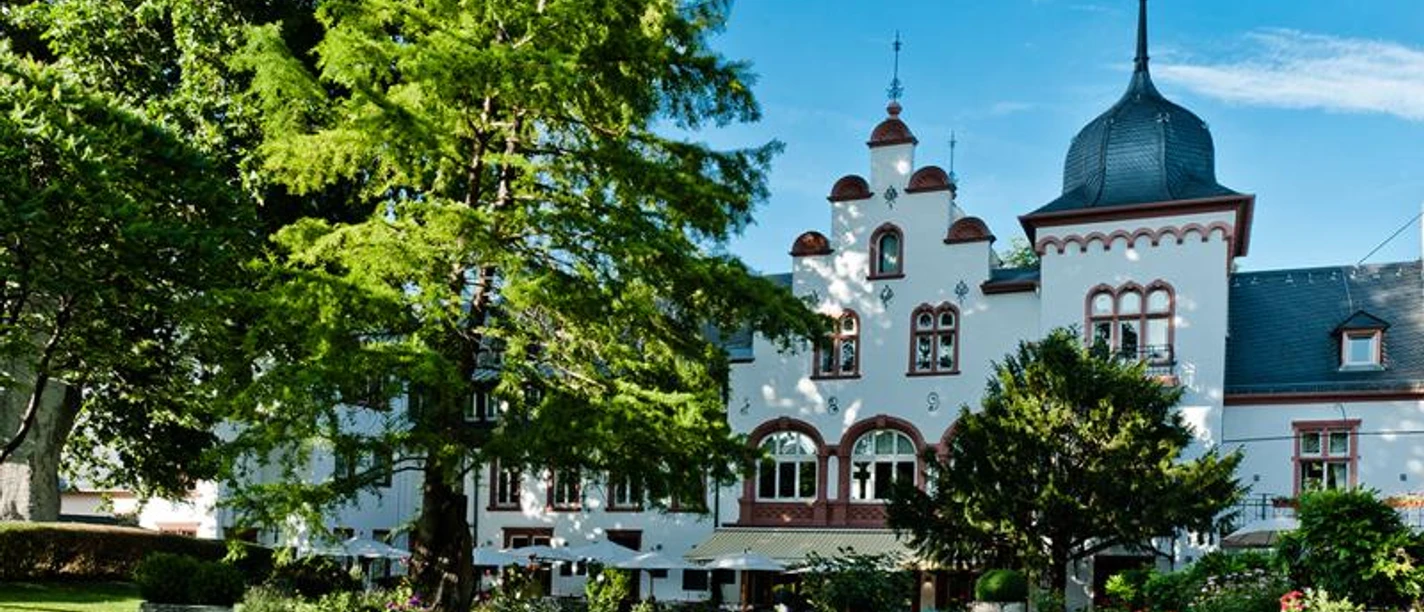 Hotel Kronenschlösschen Ein elegantes Hotel "Kronenschlösschen" mit Garten, Bäumen und Liegestühlen.