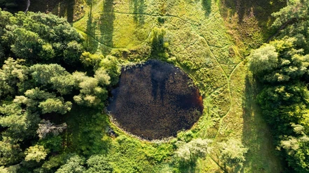 Amelinghausen_Marxener_Paradies_Drohne_Luftaufnahme_ccbysa_tl_20230810-7.JPG Ein kleiner runder See, umgeben von Wäldern und Wiesen, aus der Luft fotografiert.