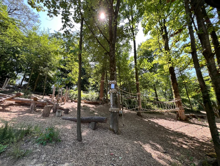 Niedrigseilgarten in Heiligenhaus Niedrigseilgarten in Heiligenhaus mit hölzernen Kletterelementen, umgeben von Bäumen und Sonnenlicht.