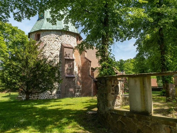 Kirche Feldstein Die Kirche ist aus Stein gebaut und von vielen grünen Bäumen umgeben. Der runde Turm hat ein grünes Kupferdach. Ein kleiner Steinweg führt seitlich vorbei. Eine friedliche und ruhige Atmosphäre herrscht hier.