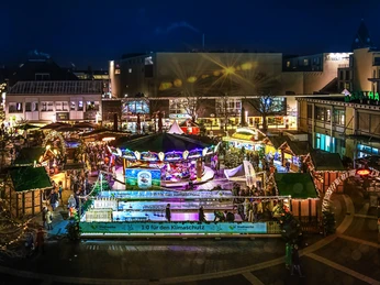 Das Langenfelder Weihnachtsdorf Weihnachtsmarkt bei Nacht in Langenfeld, beleuchtet mit Ständen, Karussell und Schlittschuhbahn.
