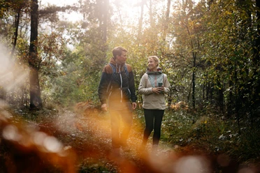 Wandern im Osnabrücker Land Zwei Personen wandern im sonnendurchfluteten Wald bei herbstlicher Stimmung.