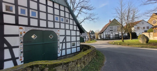 Vierständerscheune Hüllhorst Ein klassisches Fachwerkensemble mit schwarzweißen Fassaden säumt eine ruhige Dorfstraße.