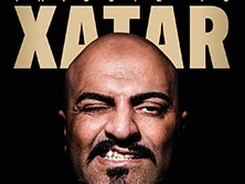 Das Bild zeigt eine frontal aufgenommene Nahaufnahme des muskulären Gesichts eines Mannes mit Glatze, der eine Grimasse zieht und die Zähne zeigt.