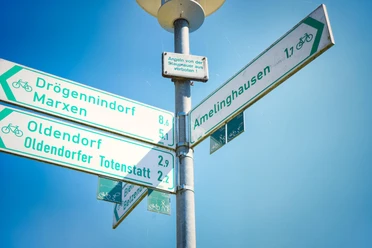 50-jahre-samtgemeinde-amelinghausen-cover (15).JPG Ein Verkehrsschild zeigt Wege zu verschiedenen Orten. Drögennindorf, Marxen, Oldendorf und Amelinghausen sind ausgeschildert. Diese Orte sind zum Radfahren geeignet. Ein klarer Himmel ist sichtbar.