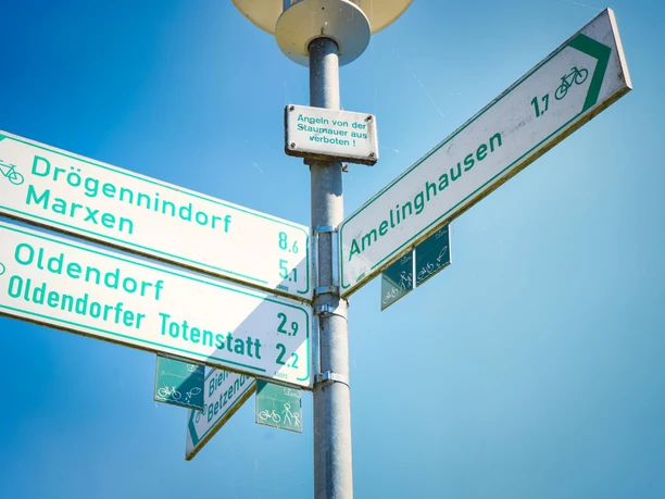 50-jahre-samtgemeinde-amelinghausen-cover (15).JPG Ein Verkehrsschild zeigt Wege zu verschiedenen Orten. Drögennindorf, Marxen, Oldendorf und Amelinghausen sind ausgeschildert. Diese Orte sind zum Radfahren geeignet. Ein klarer Himmel ist sichtbar.