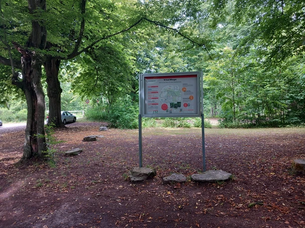 Het informatiebord van VitalWegen staat onder grote bomen op de parkeerplaats in het stadsbos van Einbeck.