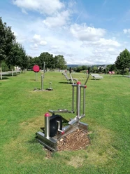 Ein Ganzkörpertrainer auf der Wiese, im Hintergrund weitere Fitnessgeräte des Beverunger Bewegungsparcours.
