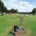 Ein Ganzkörpertrainer auf der Wiese, im Hintergrund weitere Fitnessgeräte des Beverunger Bewegungsparcours.