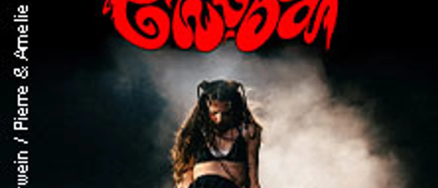 Eine Künstlerin performt live auf einer Bühne, umgeben von dramatischem Rauch und rotem Schriftzug.