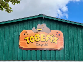 Tobefix Ein Bild von einem grünen Gebäude mit einem auffälligen Schild und der Aufschrift "TOBEFIX Langwedel".