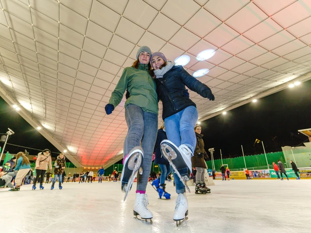 Zwei Jugendliche laufen Schlittschuh in der beleuchteten Schierker Feuerstein Arena.