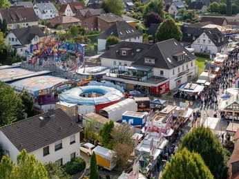 Gesmolder Kirmes von oben.jpg Luftaufnahme eines belebten Jahrmarkts mit bunten Fahrgeschäften und Besuchern.