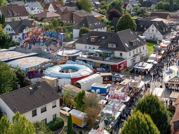 Gesmolder Kirmes von oben.jpg Luftaufnahme eines belebten Jahrmarkts mit bunten Fahrgeschäften und Besuchern.